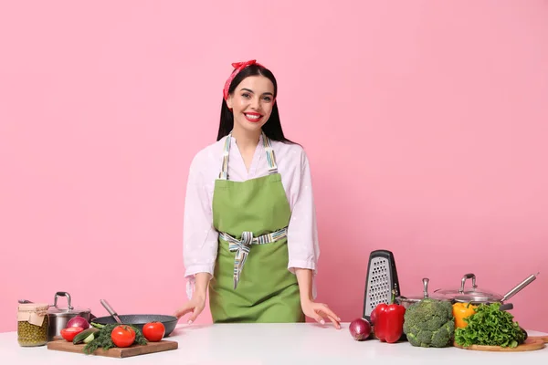 Молодая Домохозяйка Белым Столом Посудой Продуктами Розовом Фоне — стоковое фото