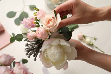 Çiçekçi beyaz masada güzel bir buket oluşturuyor, yakın plan.