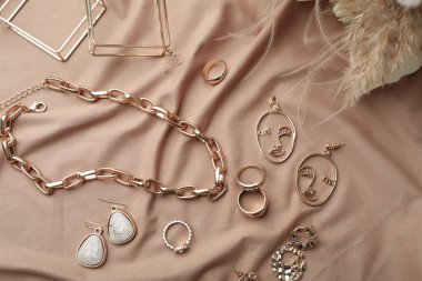 Açık kahverengi kumaş üzerinde şık altın bijouterie, düz.