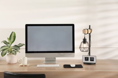 Boş ekranlı modern bilgisayar ve ahşap masa üzerindeki çevreseller.