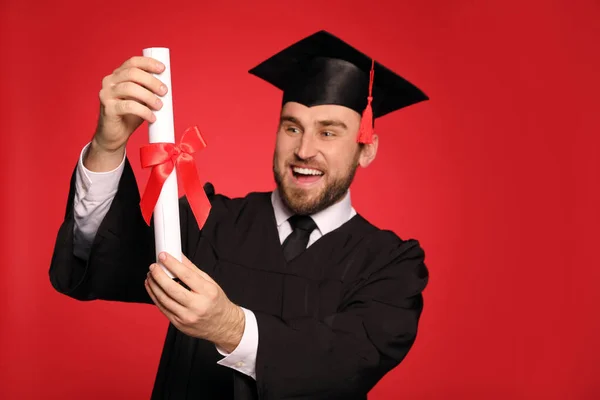 Gelukkige Student Met Afstudeerhoed Tegen Rode Achtergrond Focus Diploma — Stockfoto