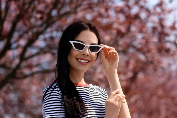 Ładna Młoda Kobieta Okularach Przeciwsłonecznych Pobliżu Pięknych Kwitnących Drzew Świeżym — Zdjęcie stockowe