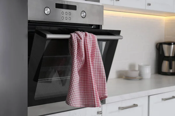 Clean checkered towel on oven door in kitchen