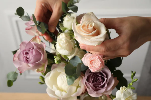 Florist creating beautiful bouquet with roses indoors, closeup