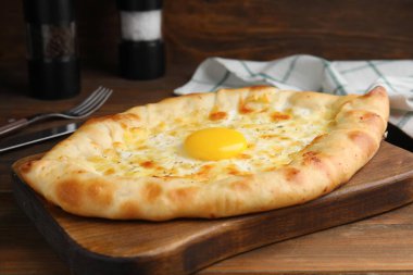 Taze ev yapımı khachapuri peynirli ve yumurtalı ahşap masa, yakın plan.