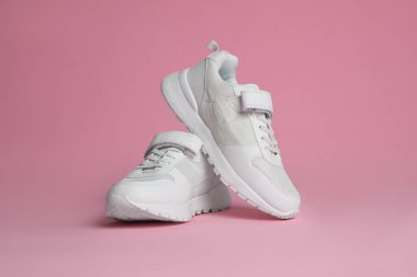 Pembe arka planda şık bir çift spor ayakkabı.
