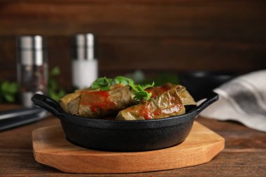 Tahta masada domates soslu lezzetli doldurulmuş üzüm yaprakları.