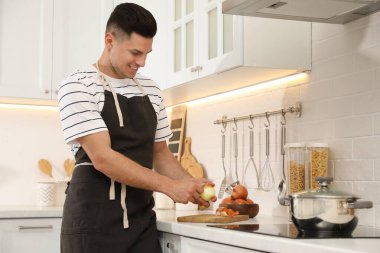 Man peeling onion at kitchen counter. Preparing vegetable