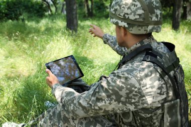 Ormanda tablet kullanan sırt çantalı asker