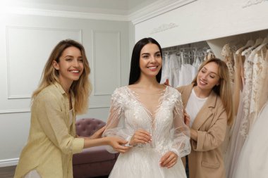 Gelin ve arkadaşları butikte gelinlik seçiyor.