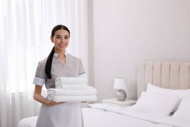 Otel odasında temiz havlu yığını olan oda hizmetçisi. Metin için alan