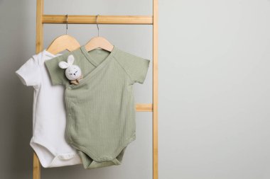 Bebek kıyafetleri ışık duvarının yanındaki merdivende asılı, mesaj için yer var.