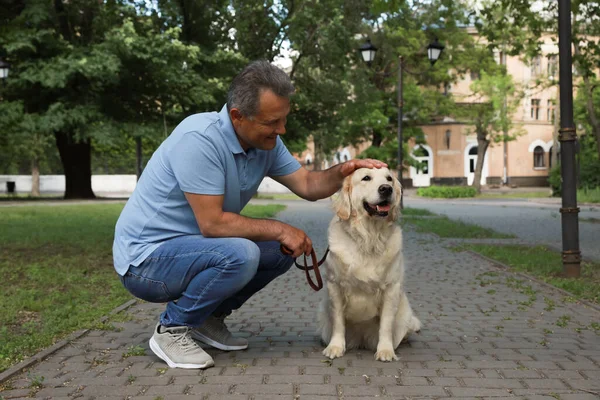 幸せなシニア男とともに彼のゴールデンレトリバー犬で公園 — ストック写真