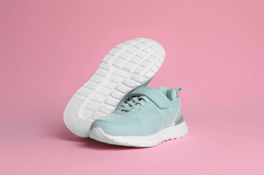 Pembe arka planda şık bir çift spor ayakkabı.