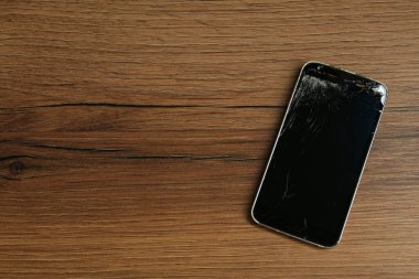 Tahta masadaki hasarlı akıllı telefon, yazı için yeri olan üst görünüm. Aygıt onarımı
