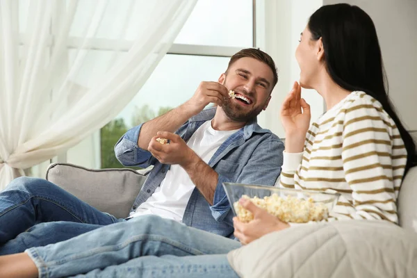 Happy couple watching movie with popcorn at home