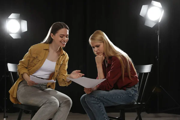 Professional actresses reading their scripts during rehearsal in theatre