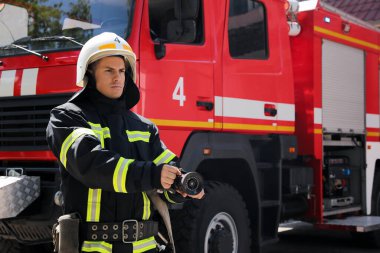 Dışarıdaki itfaiye aracının yanında yüksek basınçlı su jeti olan itfaiyeci.
