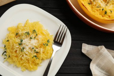 Siyah ahşap masada servis edilen peynirli ve kekikli lezzetli spagetti.