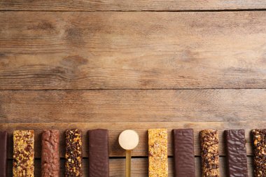 Farklı lezzetli barlar ve tahta masada bir kepçe protein tozu. Metin için boşluk