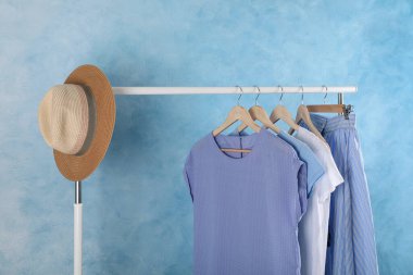 Açık mavi duvarın yanında şık kıyafetlerle dizilin.