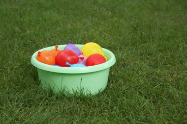 Yeşil çimlerin üzerinde su bombalarıyla dolu bir leğen. Metin için boşluk