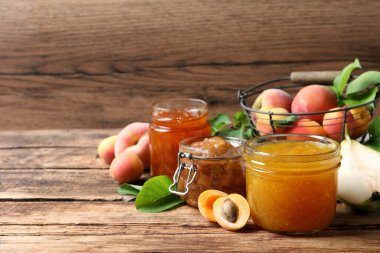 Farklı reçelli kavanozlar ve ahşap masada taze meyveler. Metin için boşluk