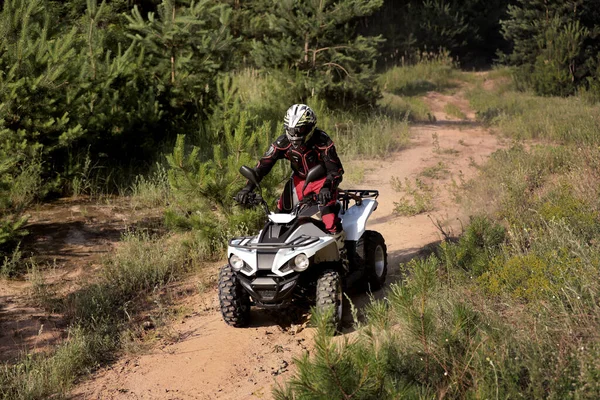 森の近くの砂の道で現代のクワッドバイクを運転する男 極端なスポーツ — ストック写真