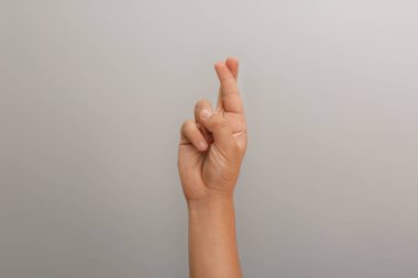 Genç çocuk açık gri arka planda şans diliyor, yakın plan.