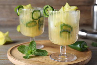Baharatlı kokteyl, jalapeno ve ahşap masada karambola.