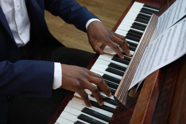 Kapalı mekanda piyano çalan Afro-Amerikalı bir adam, yakın plan. Yetenekli müzisyen.