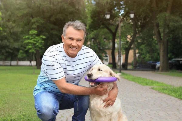 幸せなシニア男とともに彼のゴールデンレトリバー犬で公園 — ストック写真