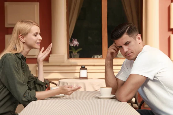 Man having boring date with talkative woman in outdoor cafe