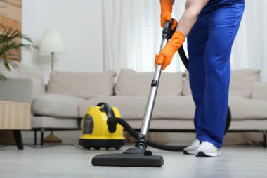 Kapıcı üniformalı. Yerleri süpürüyor. Kapıları kapatıyor.