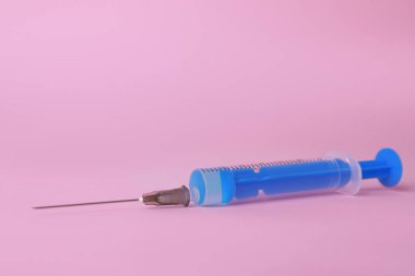 Pembe zemin üzerinde iğne ve ilaç bulunan tek kullanımlık şırınga, metin için boşluk