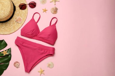 Pembe arka planda şık bikini ve plaj aksesuarları, düz yatış. Metin için boşluk