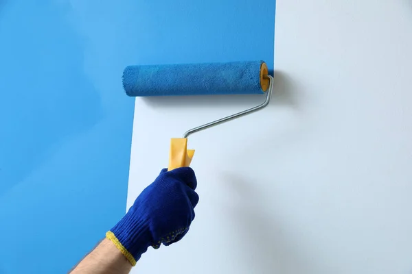 Mann Trägt Hellblaue Farbe Mit Rollerpinsel Auf Weiße Wand Auf — Stockfoto