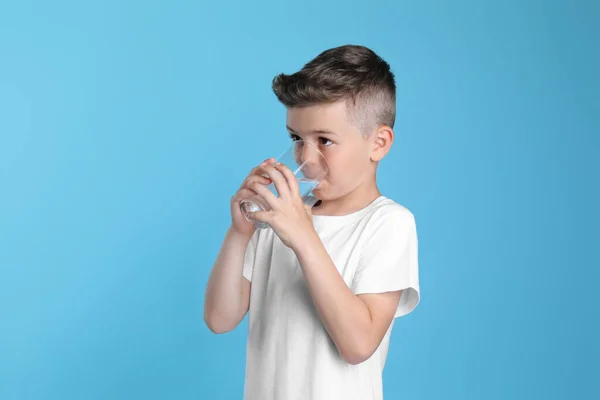 Söt Liten Pojke Dricksvatten Från Glas Ljusblå Bakgrund — Stockfoto