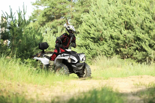 森の近くの砂の道で現代のクワッドバイクを運転する男 極端なスポーツ — ストック写真