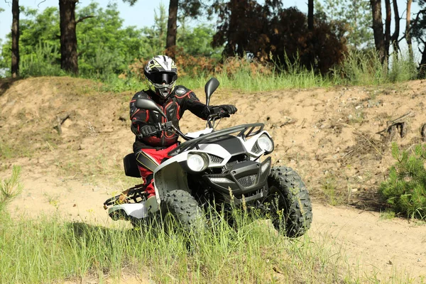 森の近くの砂の道で現代のクワッドバイクを運転する男 極端なスポーツ — ストック写真