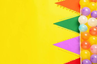 Renkli üçgen bayraklar ve sarı arka planda diğer şenlikli dekorlar, düz yatıyordu. Metin için boşluk