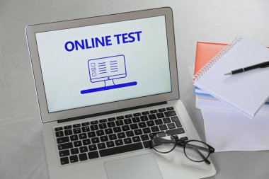 İnternette test edilen dizüstü bilgisayar, gri masada gözlük ve kırtasiye malzemeleri