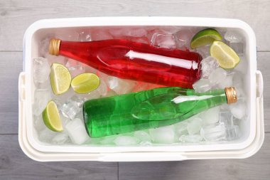Plastik kutular buz dolu, kireç ve ferahlatıcı içecekler ahşap zemin, üst manzara