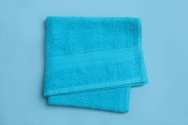 浅蓝色背景的折叠式软沙滩毛巾 顶部视图 — 图库照片