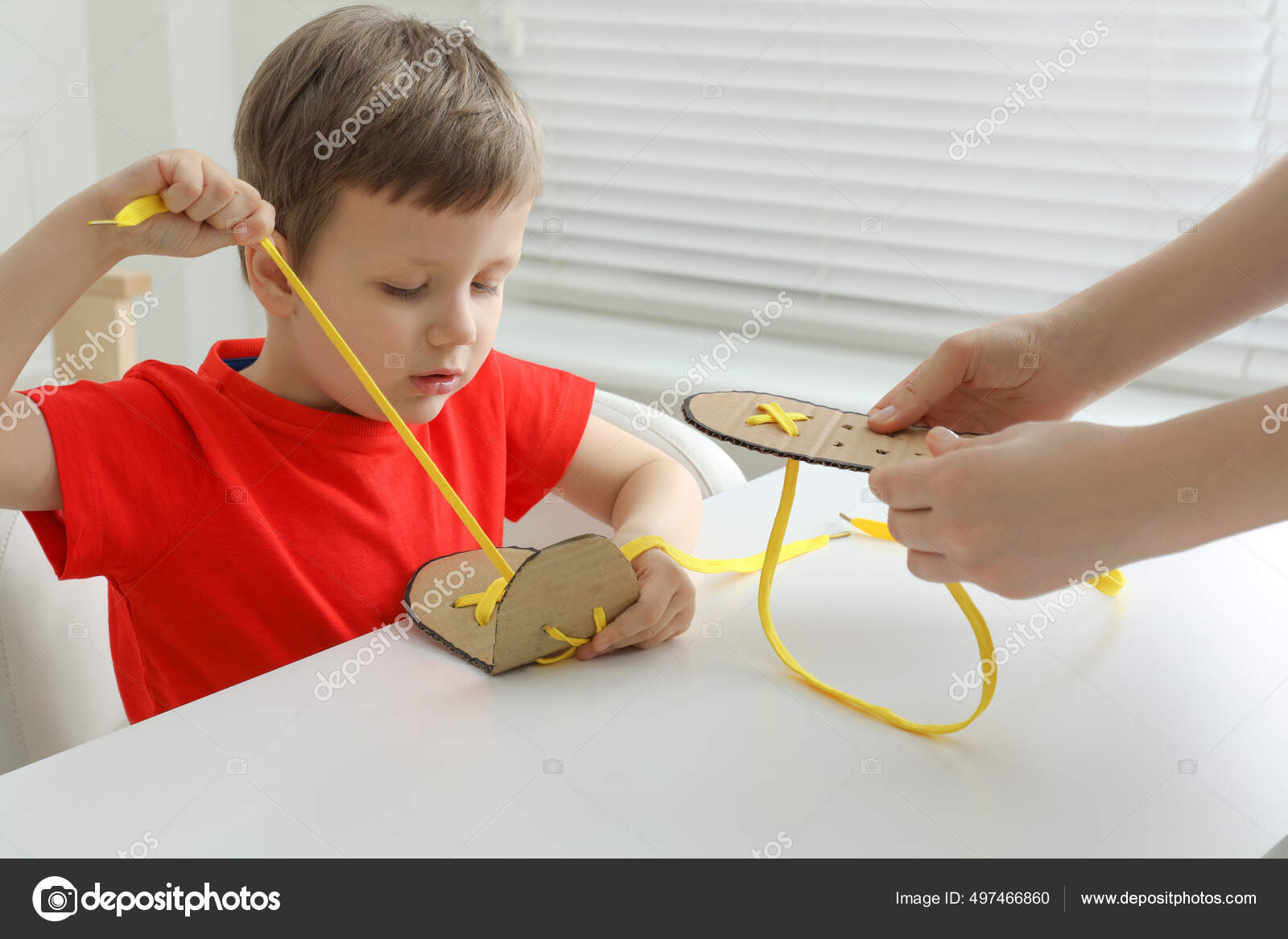 Mother Teaching Son Tie Shoe Laces Using Training Cardboard
