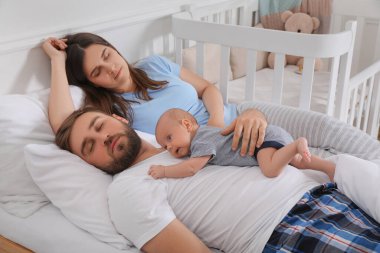 Bebekleri evde uyurken yorgun ve genç ebeveynler.
