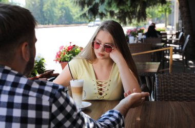 Genç bir kadın, açık kafede bir adamla sıkıcı bir randevu yaşıyor.