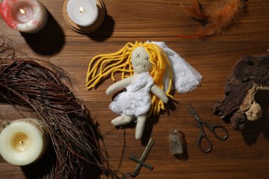 Ahşap arka planda tören eşyalarıyla çevrili iğneli gelin voodoo bebeği.
