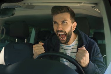 Stresli sinirli adam modern arabanın sürücü koltuğunda, ön camdan bakıyor.