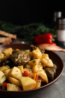 Gri masadaki toprak kabında patatesle pişirilmiş lezzetli yemekler.